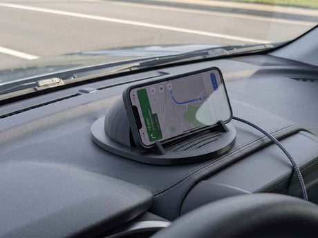 Phone on a car dashboard with a wireless charging pad with covert video surveillance