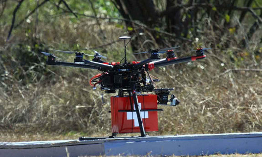 Drone with a red box featuring a white cross on a road with blurred natural background