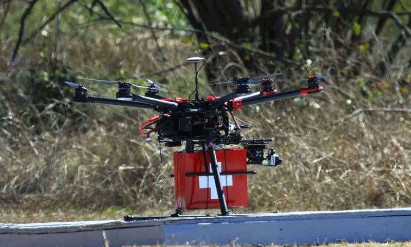 Drone with a red box featuring a white cross on a road with blurred natural background