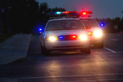 Two police cars with flashing lights on a road at night.
