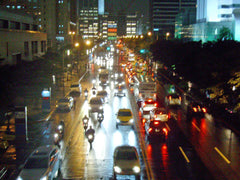 Busy city street at night with traffic and illuminated buildings.