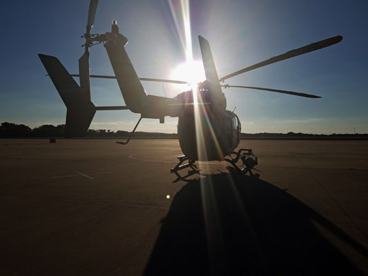 Helicopter on a runway with sun shining through its blades