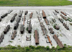 Collection of metal beams and structures on a concrete surface with grass in the background