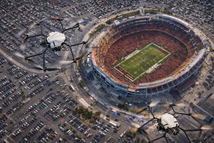 A drone flying over a large stadium with a football field.