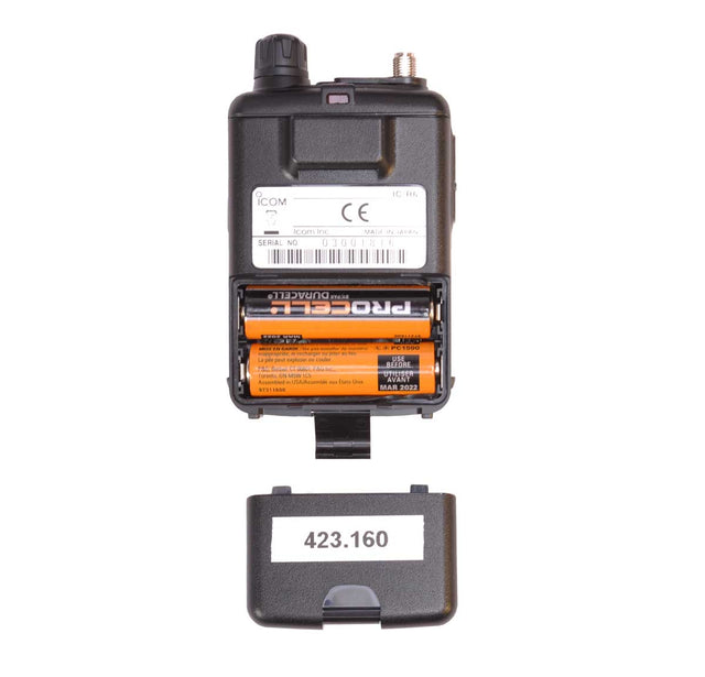 A black electronic covert body wire receiver with its battery compartment open, showing two orange ProGrade AA batteries inside, alongside a separate black cap or cover labeled with the number 423.160 on a white background.