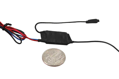 A small black body wire module with attached wires and a connector, shown next to a coin for scale on a plain white background.