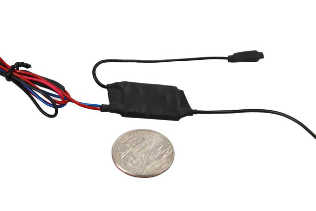 A small black body wire module with attached wires and a connector, shown next to a coin for scale on a plain white background.