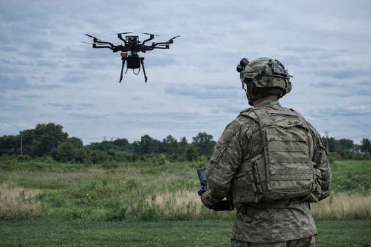 Person in military uniform operating a drone in an open field