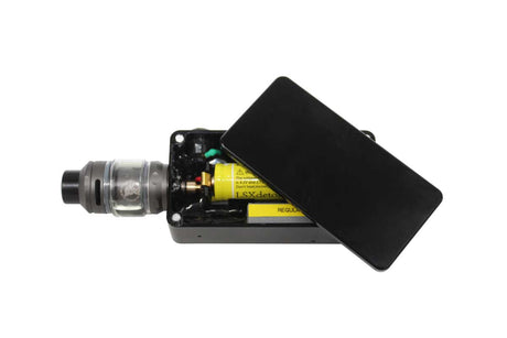 A black covert body worn camera vape device with its lid propped open, showing a clear tank and internal yellow battery components, isolated on a white background.