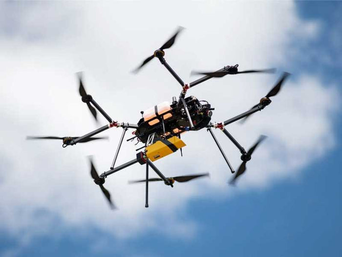 Hexacopter drone flying against a cloudy sky
