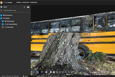 A digital preview of a 3D printed model or render showing a yellow school bus with a large tree stump in the foreground, displayed within a software interface with a dark gray left sidebar.