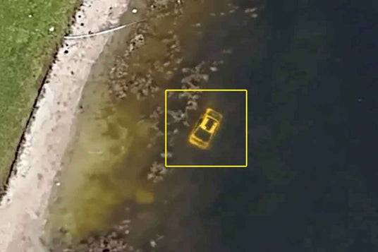 A yellow taxi cab is partially submerged in water, with a yellow box around it for emphasis.
