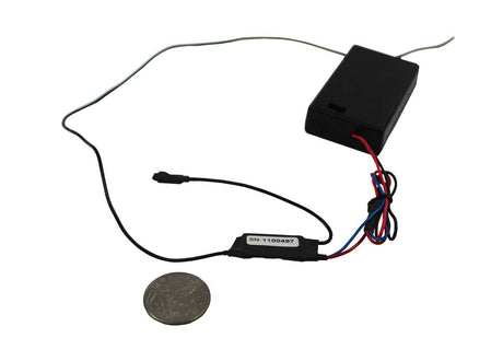 A small black police body wire module with attached wires and a coin shown below for scale, photographed on a plain white background.