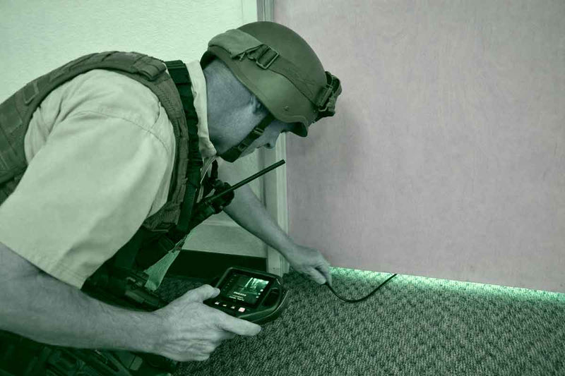 Person in tactical gear using a device on a wall
