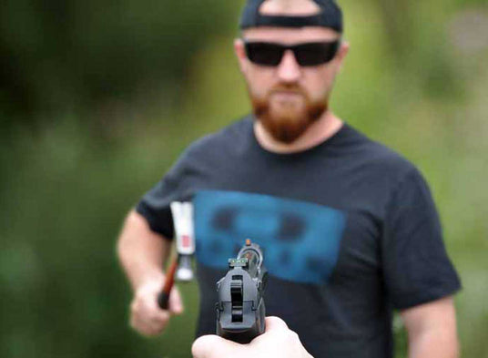 Man holding a handgun with a active threat in a blurred natural background
