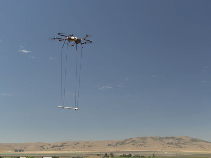 Drone lifting a payload in the sky with a clear blue background