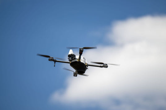 Drone flying against a blue sky with clouds
